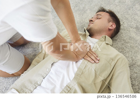 CPR chest compressions on unconscious man during emergency first aid training 136546586