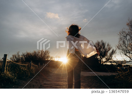 Person Running Toward Sunset on a Rural Path 136547059