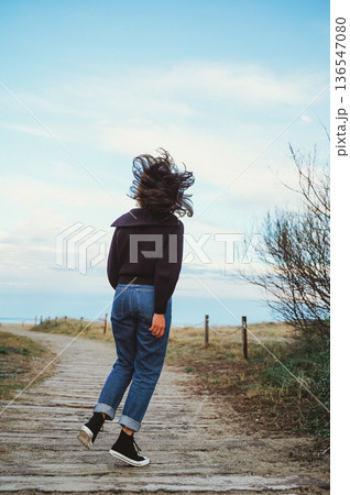 Woman Walking on Path with Hair Blowing in Wind Woman Walking on Path with Hair Blowing in Wind 136547080