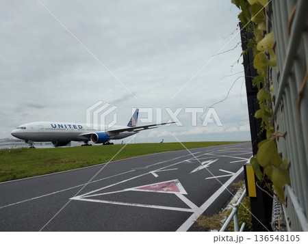 滑走路を走行するユナイテッド航空の大型旅客機 空港のフェンス越しに見る旅の情景 滑走路を走行するユナイテッド航空の大型旅客機 空港のフェンス越しに見る旅の情景 136548105