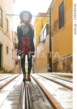 Young woman standing on tram tracks in historic lisbon street Young woman standing on tram tracks in historic lisbon street 136548548