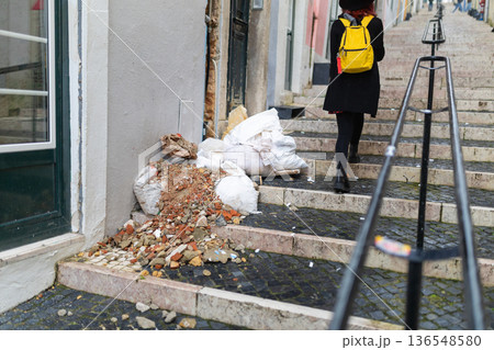Tourist walking up urban stairs past construction debris 136548580