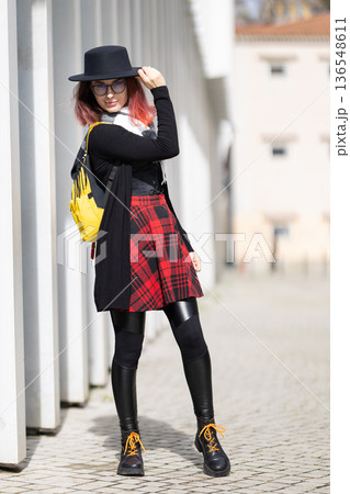 Stylish woman wearing hat standing on urban street 136548611