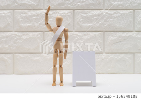 タスキをかけて手を挙げてあいさつする選挙の候補者 136549188