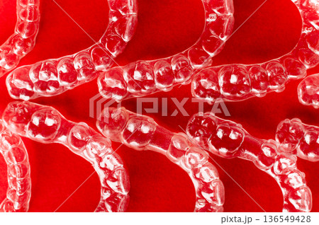Extreme macro close-up of clear braces. Multiple aligners against a colored background, close-up with a shallow depth of field. 136549428