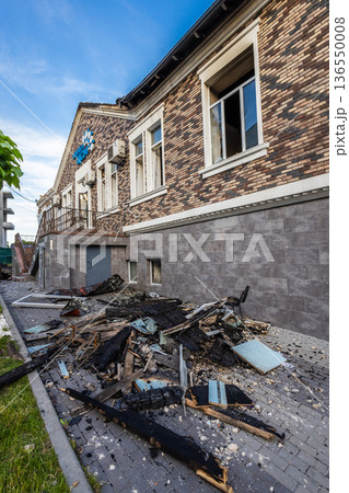 Bila Tserkva, Kyiv region, Ukraine - 09.06.2025: Burned debris scattered outside a damaged brick building with broken windows and charred materials showing severe destruction. Bila Tserkva, Kyiv region, Ukraine - 09.06.2025: Burned debris scattered outside a damaged brick building with broken windows and charred materials showing severe destruction. 136550008
