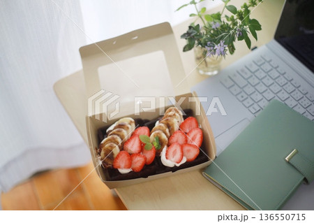 デスクの上に置かれたバナナといちごのヘルシースイーツとノートパソコン 136550715