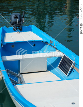 Blue motorboat equipped with a small solar panel and outboard engine floating on calm water,sustainable boating concept and clean renewable energy use Blue motorboat equipped with a small solar panel and outboard engine floating on calm water,sustainable boating concept and clean renewable energy use 136552732