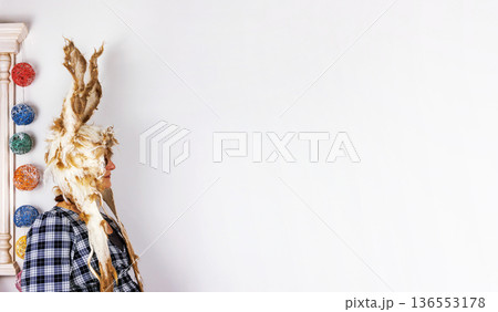 Woman wearing felted wool bunny hat with long ears standing against a white wall with copy space 136553178