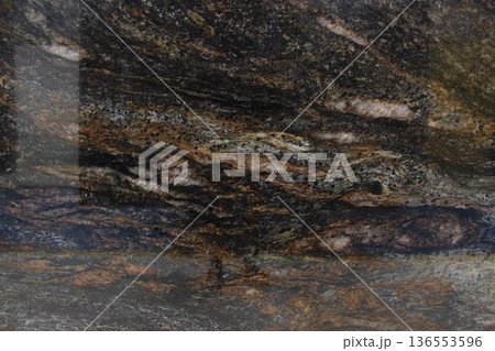 Close-up of a Titanium granite slab showing unique mineral composition with a blend of dark colors and shimmering copper accents. 136553596
