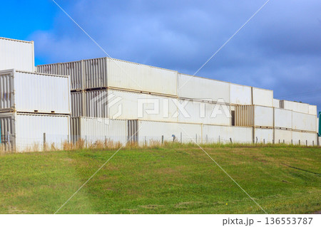 Storage containers stacked in field with few clouds near shipping area 136553787