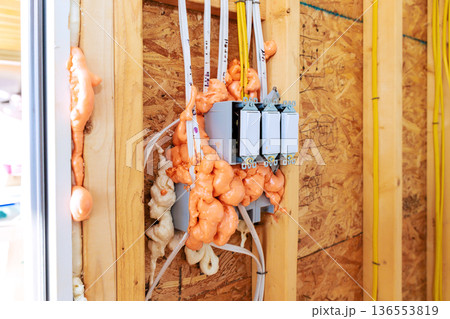 Electrical work in house with fire proof foam insulation covering wires switches on wooden wall Electrical work in house with fire proof foam insulation covering wires switches on wooden wall 136553819
