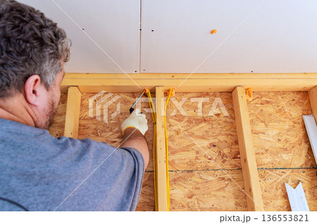 Workshop in house shows worker working on wooden wall framing at construction site Workshop in house shows worker working on wooden wall framing at construction site 136553821