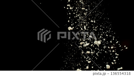Falling white powder, flour particles floating and dispersing in air, isolated on black background. Detailed texture and dynamic dust cloud effect. 136554318