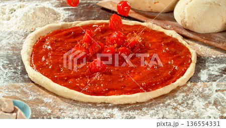 Fresh sliced tomatoes falling into rich tomato sauce on raw pizza dough. Cinematic food preparation shot capturing splash, texture and motion in detail. Fresh sliced tomatoes falling into rich tomato sauce on raw pizza dough. Cinematic food preparation shot capturing splash, texture and motion in detail. 136554331
