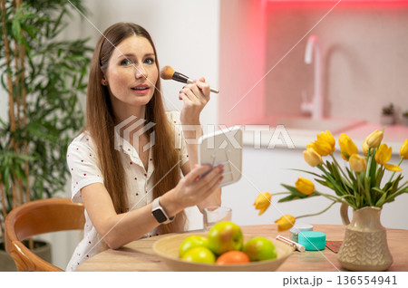 Long-haired beautiful young woman with a face brush sitting at the table 136554941