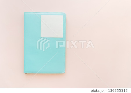 Turquoise notebook with blank sticky note on pastel background, minimal flat lay 136555515