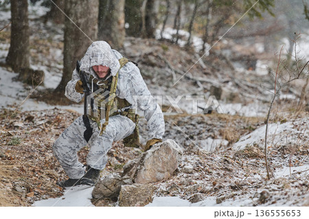 Soldier In White Winter Camouflage Patrolling Snowy Forest With Rifle During Cold Weather Operation Soldier In White Winter Camouflage Patrolling Snowy Forest With Rifle During Cold Weather Operation 136555653
