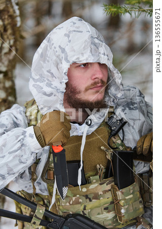 Soldier in Winter Camouflage With Tactical Vest and Knife on Patrol in Snowy Forest 136555671