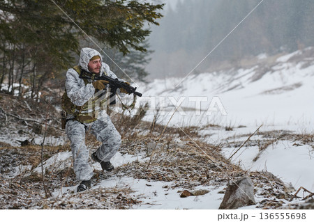 Soldier In Winter Camouflage Patrols Snowy Forest With Rifle During Cold Weather Training Exercise Soldier In Winter Camouflage Patrols Snowy Forest With Rifle During Cold Weather Training Exercise 136555698