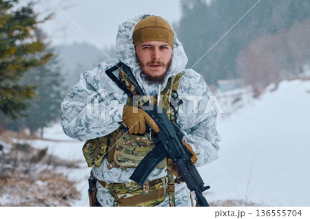 Soldier In White Winter Camouflage Holding Assault Rifle During Snowy Forest Patrol 136555704