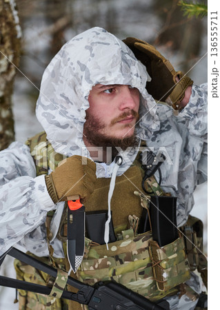 Bearded Soldier In Winter White Camouflage With Tactical Gear Knife And Rifle In Snowy Forest 136555711
