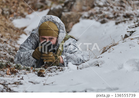 Soldier in Winter Camouflage Prone With Rifle Aiming Through Snow in Forest Trench 136555739