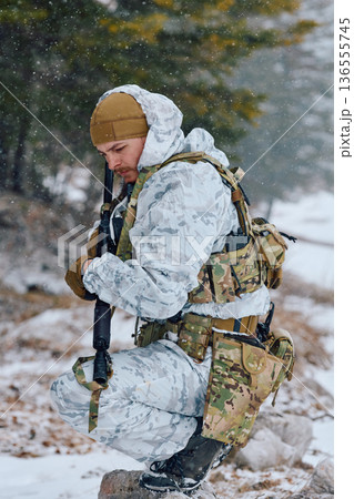 Soldier In Winter Camouflage Gear Kneeling With Rifle During Snowy Military Training Exercise Soldier In Winter Camouflage Gear Kneeling With Rifle During Snowy Military Training Exercise 136555745