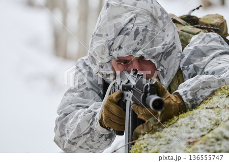 Soldier In White Winter Camouflage Aiming Rifle While Lying Prone In Snowy Forest 136555747