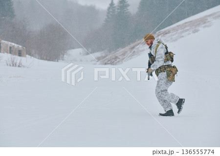 Soldier In White Camouflage Walking Through Snowy Winter Landscape With Tactical Gear And Rifle 136555774