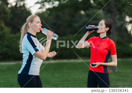 Women drink water during outdoor workout session 136556341