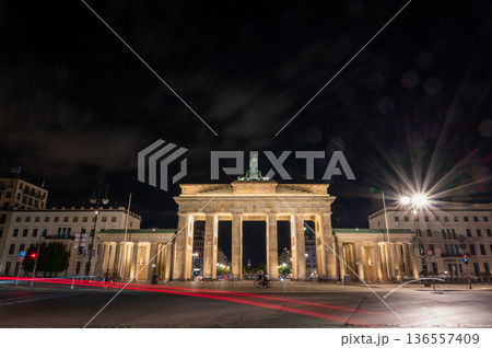 Berlin, germany, august 14, 2023. Brandenburg gate in berlin standing illuminated at night, featuring historic architecture with long exposure car light trails Berlin, germany, august 14, 2023. Brandenburg gate in berlin standing illuminated at night, featuring historic architecture with long exposure car light trails 136557409