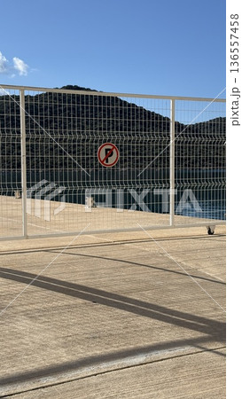 Fence with no entry sign overlooking serene lake and mountains under clear blue sky background Fence with no entry sign overlooking serene lake and mountains under clear blue sky background 136557458