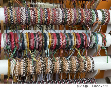 Colorful woven bracelets displayed on multiple rows of a market stall as a creative background 136557466