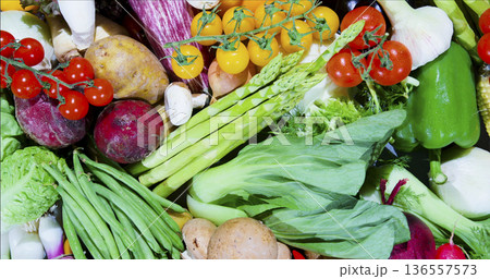 Fresh vegetables and fruits gathered together on a table for cooking or meal preparation in a kitchen setting 136557573