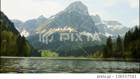 Visit to a mountain lake with clear water and tall peaks near the trees during a sunny day in spring 136557581