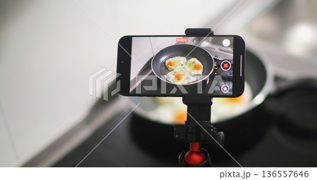 Person uses a smartphone to record cooking eggs in a frying pan in a kitchen setting during daytime Person uses a smartphone to record cooking eggs in a frying pan in a kitchen setting during daytime 136557646