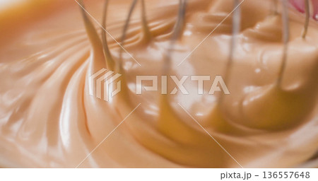 Mixing cream in a bowl with a whisk during a kitchen activity in the morning light 136557648