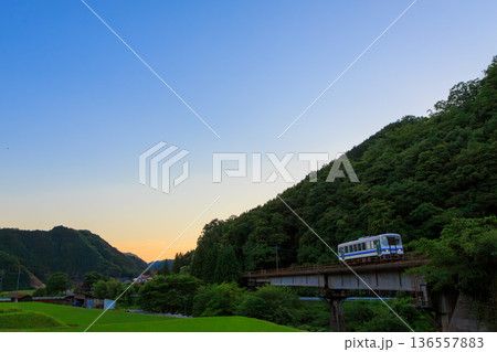 夕闇迫る山間を走る三江線の気動車 136557883