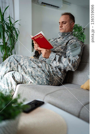 Soldier relaxing on sofa reading a book about Moravia Soldier relaxing on sofa reading a book about Moravia 136559066