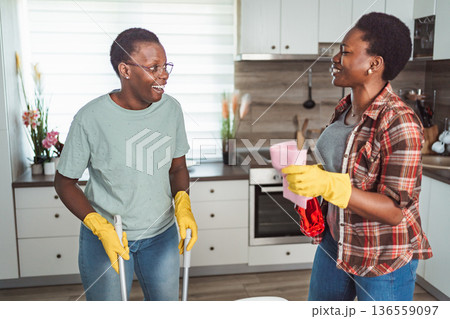 Two cheerful black women cleaning the kitchen and smiling Two cheerful black women cleaning the kitchen and smiling 136559097