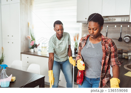 Two Young Women Cleaning Kitchen Together with Cleaning Products 136559098