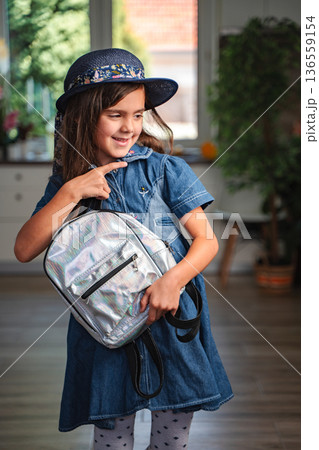 Smiling student showing her new backpack at home Smiling student showing her new backpack at home 136559154