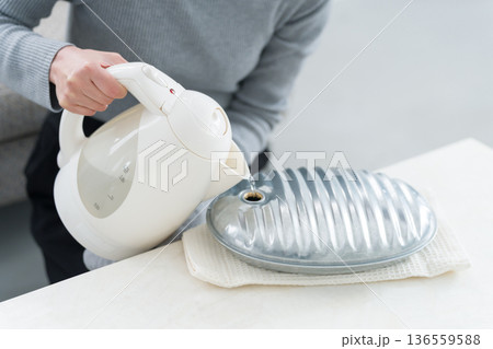 湯たんぽにお湯を入れる冷え性の女性 136559588