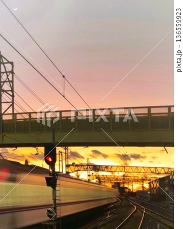 夕暮れの鉄道を走り去る電車の光跡と三日月 136559923