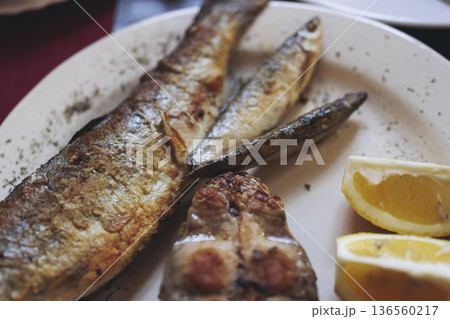 Montenegrin cuisine, fish assortment platter, fried grilled crucian carp steak, roasted pastrmka and bleak on plate with lemon and salad served in a restaurant in Montenegro, Skadar lake, Virpazar 136560217