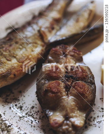 Montenegrin cuisine, fish assortment platter, fried grilled crucian carp steak, roasted pastrmka and bleak on plate with lemon and salad served in a restaurant in Montenegro, Skadar lake, Virpazar 136560218