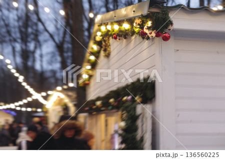 Christmas market with illuminated food stalls, gift shops and kiosks, New Year outdoor fair decorations, garlands and festoons, Xmas atmosphere, retail and store illumination, decor in Europe city Christmas market with illuminated food stalls, gift shops and kiosks, New Year outdoor fair decorations, garlands and festoons, Xmas atmosphere, retail and store illumination, decor in Europe city 136560225