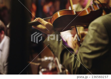 Concert view of violinist with vocalist and musical band, fiddler performing classical music, symphony orchestra performing music, violin player on stage in a club, music arena hall, fiddle and bow 136560237