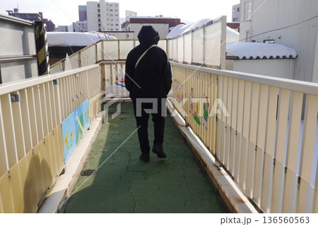 フードを被って歩く男性(後ろ姿) 136560563